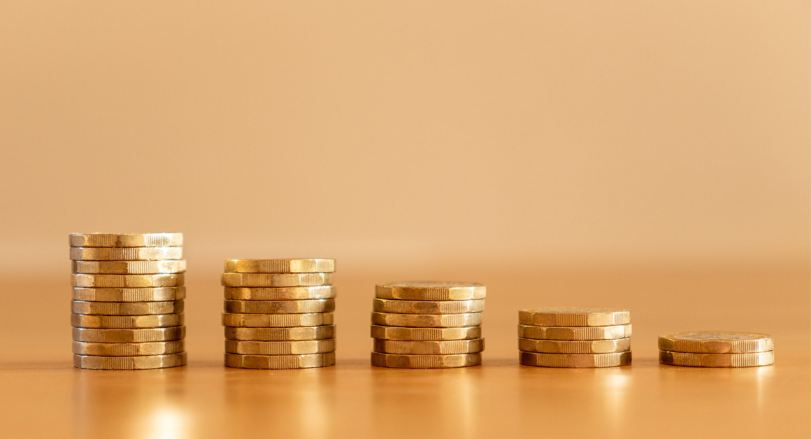 Close up of stacks of many GBP one pound coins decreasing in size as money going down symbolising the effects of inflation, UK