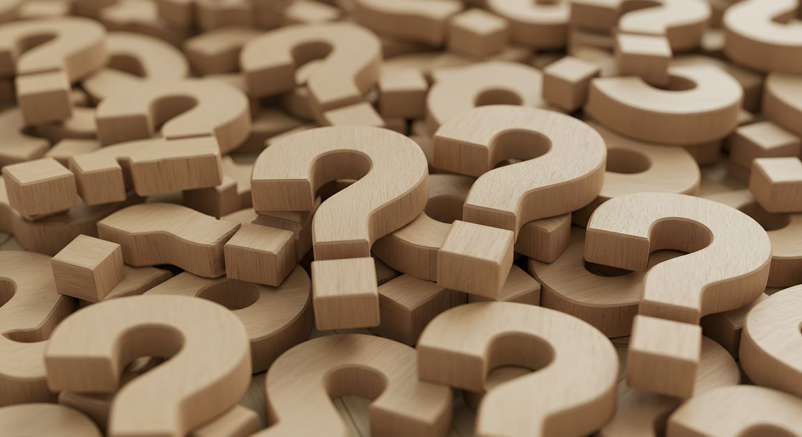 Pile of wooden question mark shapes scattered closely together, creating a textured and curious visual pattern.