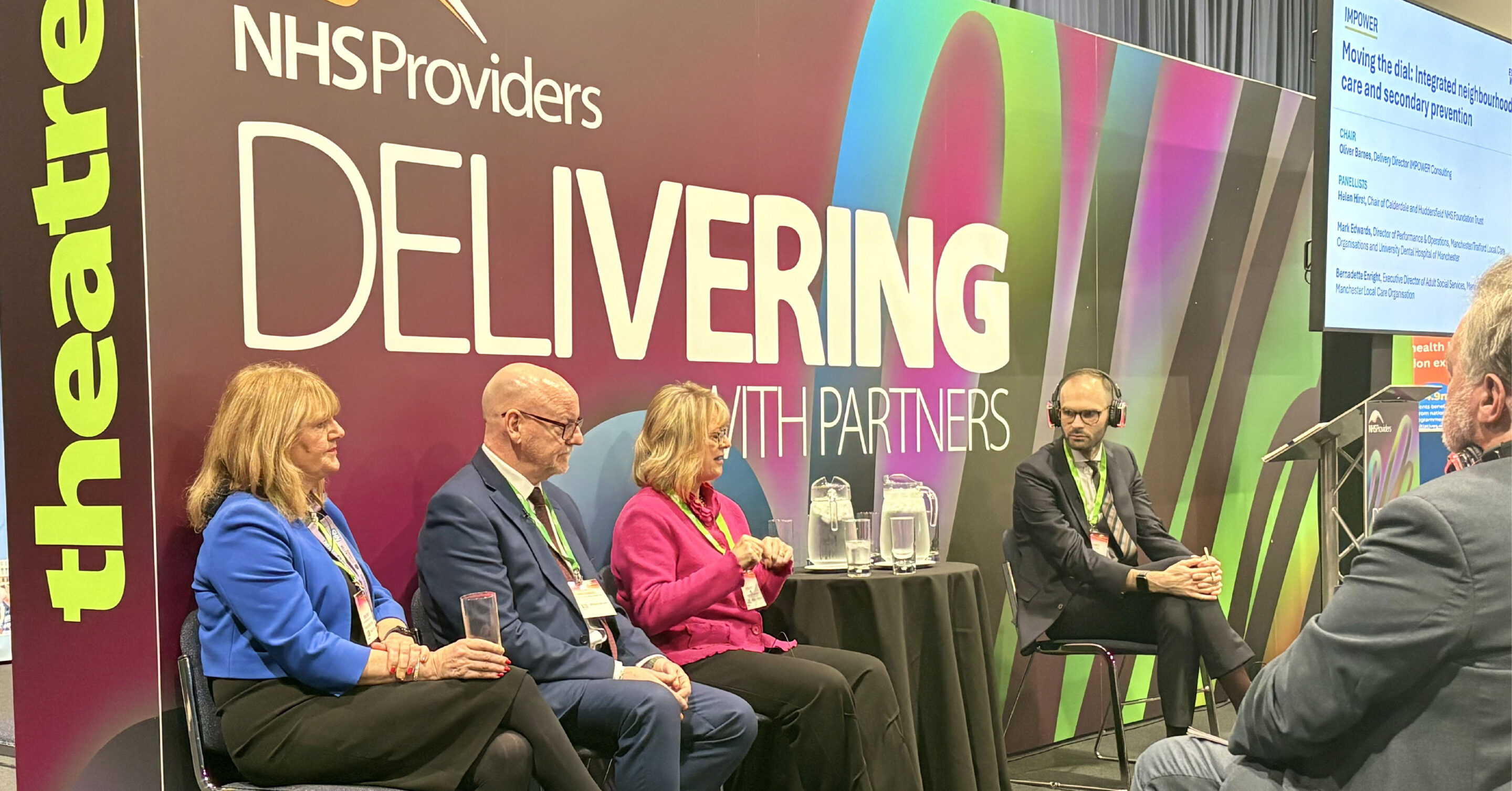 A panel of four speakers at IMPOWER's fringe session at the NHS Providers Annual Conference event titled “Delivering with Partners,” with colourful branding behind them and a presentation screen visible to the right.