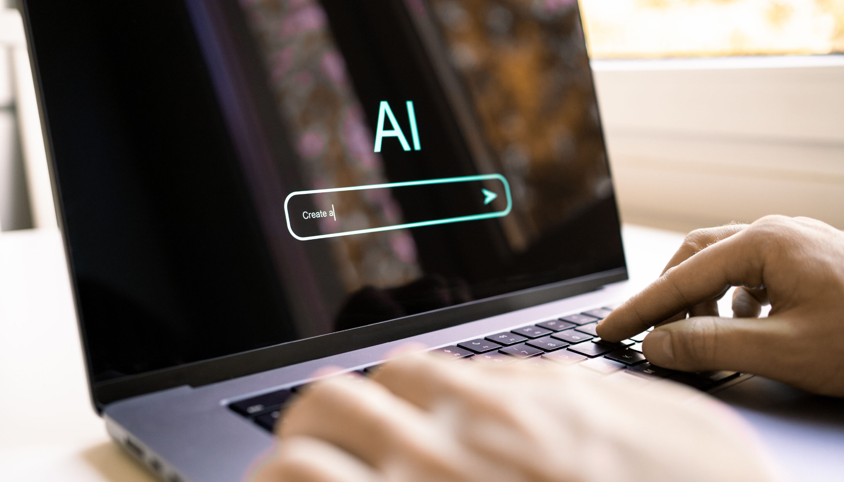 Close-up of hands typing on a laptop keyboard, with a screen displaying the word “AI” and a text input field that reads “Create a,” suggesting the use of an artificial intelligence writing or creation tool.